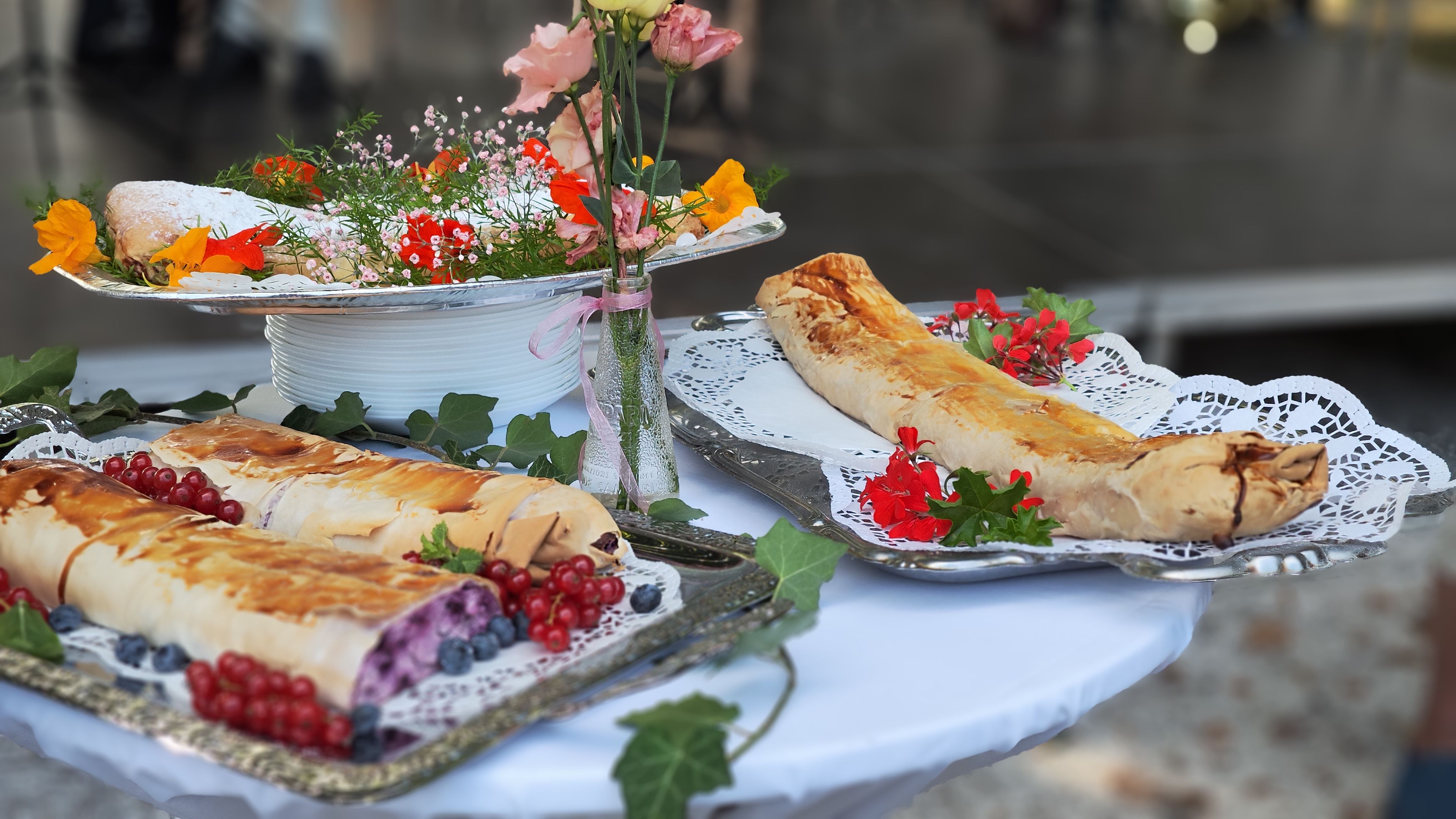 Drei Strudel auf einem Teller s, schön mit Blumen garniert.