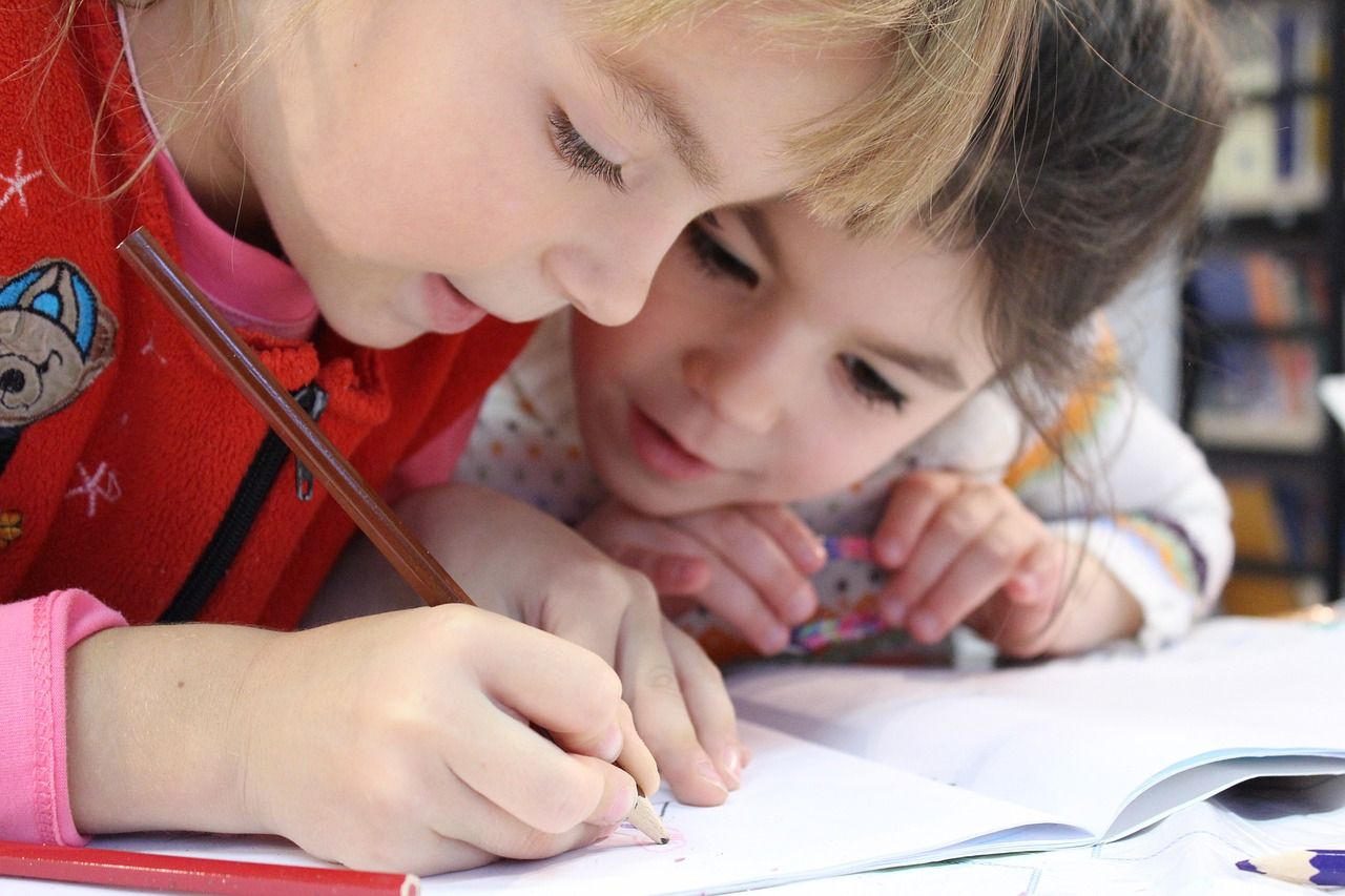 Sie sehen zwei Kinder beim erledigen der Hausaufgaben. 