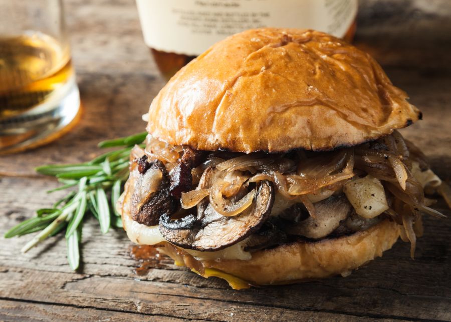 Symbolfoto: Ein Burger mit Pilzen und Zwiebel auf einem Brett