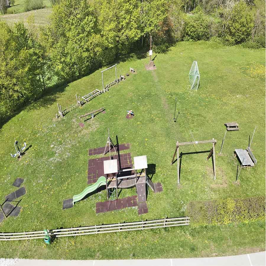 Der Spielplatz in Tangern aus der Luft. Er bietet eine Große Spielfläche, zusätzlich gibt es einen großen Kletterturm und eine Schaukel sowie zwei Hutschen. 